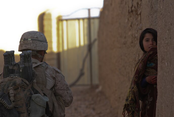 A local Afghan child peeks around the corner as Cpl. Frank Villa, a team leader with 2nd Squad, 1st Platoon, Lima Company, posts security, during a patrol in Wishtan, Feb. 22. Villa, currently deployed with 3rd Battalion, 7th Marine Regiment, talked to as many local Afghans as possible during the afternoon patrol. At times, Afghan children surrounded the patrol, asking questions in Dari and Pashto, the two most common languages in Afghanistan.