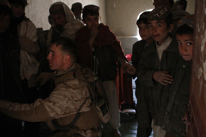 Captain Jesse Hills, the team leader for Team 3, Civil Affairs Detachment 11-2, shows students here how to write his last name in Pashto and in English Feb. 22, 2012. The Marines of Team 3 provided guidance to the local government here to help them construct a new school. The current school is made of mud and mortar, is overcrowded and only has enough capacity to hold up to sixth grade. The new school will have up to eighth grade and have more than enough room for students and teachers. Hills is from Terre Haute, Ind., and is serving under Regimental Combat Team 5 and alongside 1st Light Armored Reconnaissance Battalion in Helmand province.