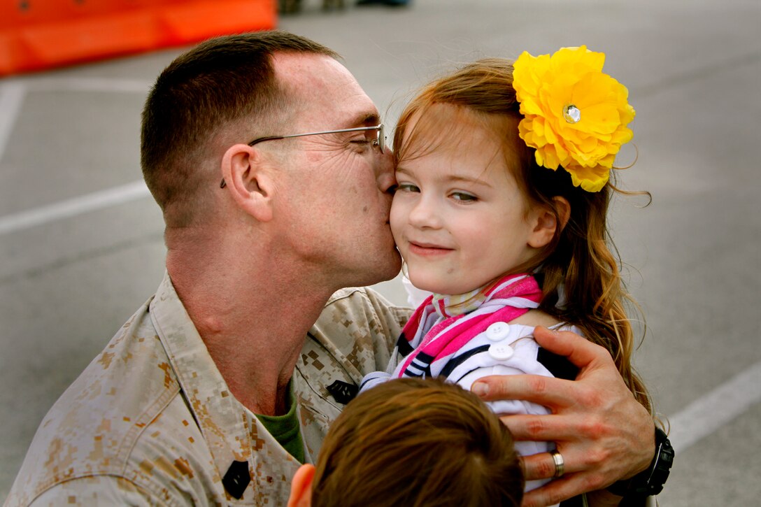 Master Sgt. Jason Vernam, an aircraft maintenance chief with Marine Wing Headquarters Squadron 2, kisses his daughter Jaydin while also embracing his son Jansen outside the Training and Education building at Marine Corps Air Station Cherry Point after returning from a year-long deployment to Afghanistan. "Being able to talk to my family on Skype and over the phone made the deployment go very smoothly," he said.  "Now that I'm back, we have to catch up on hugs, kisses and swimming."