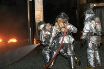 Marines from Aircraft Rescue and Fire Fighting familiarize themselves with their fire fighting equipment during a live-fire exercise Aug. 19. ARFF Marines Aboard Marine Corps Air Station New River used replica helicopters during fire training to simulate aircraft rescue.