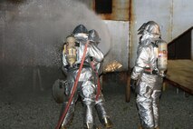 Marines from Aircraft Rescue and Fire Fighting familiarize themselves with their fire fighting equipment during a live-fire exercise Aug. 19. ARFF Marines Aboard Marine Corps Air Station New River used replica helicopters during fire training to simulate aircraft rescue.