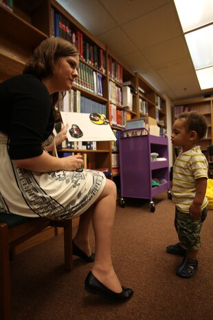 Lori Bradford, a librarian aid at the station library, hold up a board to illustrate a nursery rhyme before reading the next book to children in the youth room during the bi-monthly preschool storytime session, Aug. 11.