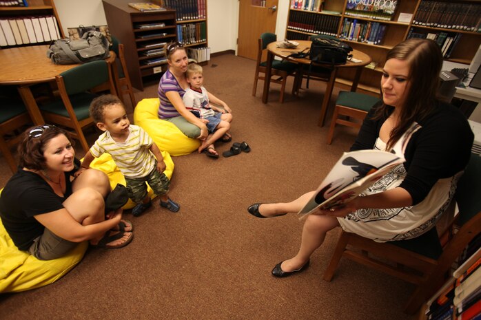 Lori Bradford, a librarian aid at the station library, reads to children in the youth room of the station library during the bi-monthly preschool storytime session, Aug. 11.