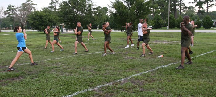 Samantha Stewart (left), a personal trainer with Semper Fit, leads the High Intensity Tactical Training class in streches after their workout, Aug. 10.