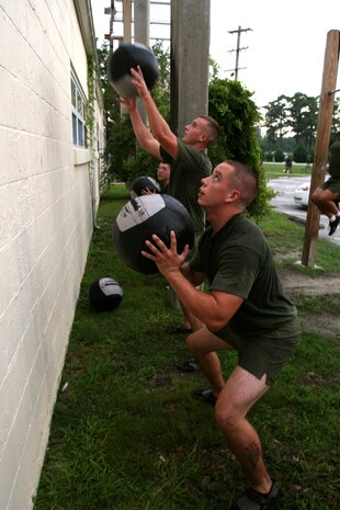 Staff Sgt. Valerian Gomez (front), Cpl. Taylor Wilkerson (middle) and Lance Cpl. Taylor Amerson participate in the High Intensity Tactical Training evaluation, do ‘wall balls,’ an exercise that combines a squat and throwing a medicine ball over the exerciser’s head, Aug. 10.