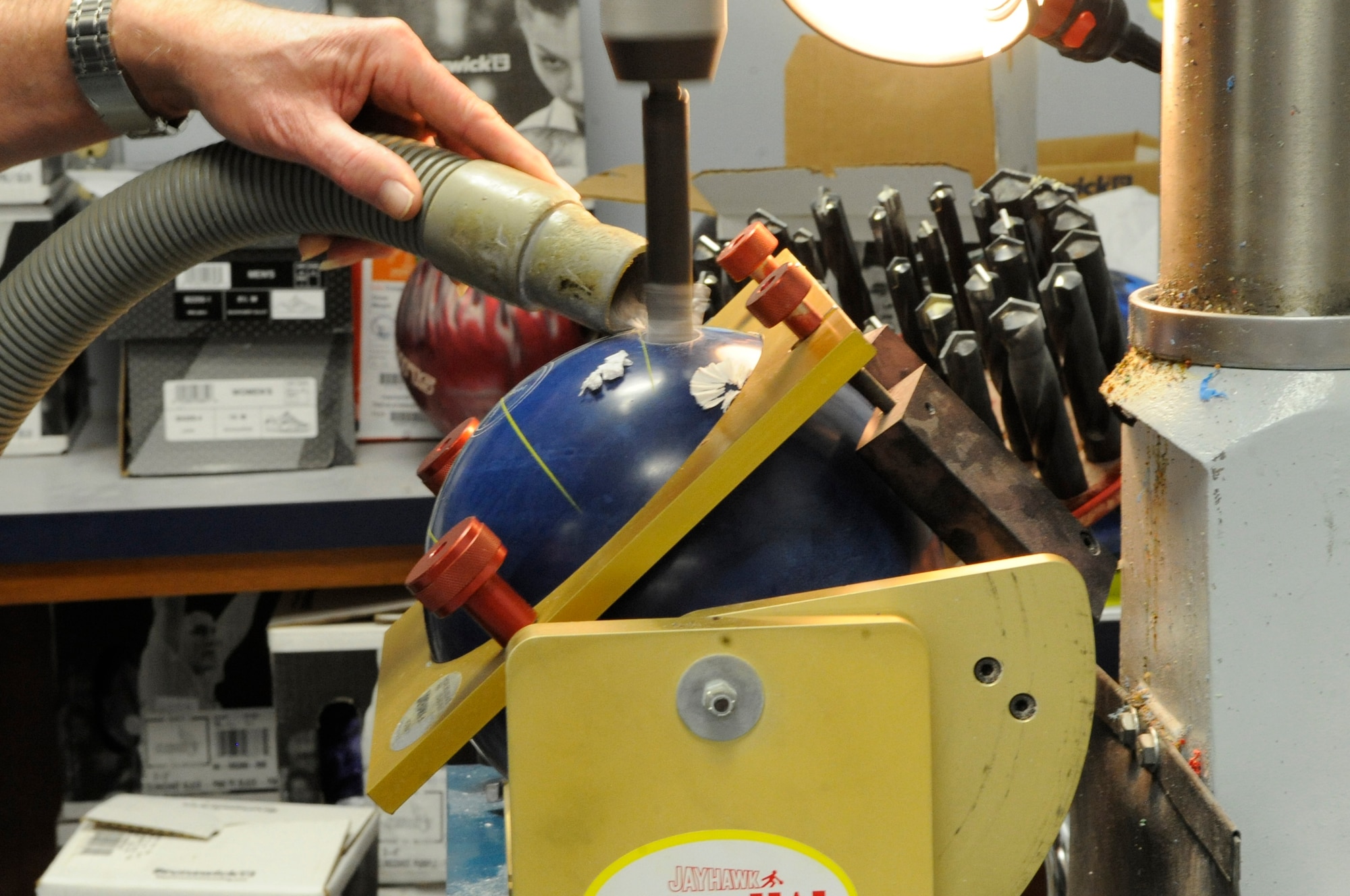 Bobby Choate, Barksdale Bowling Center manager, uses a vacuum hose to remove pieces of a bowling ball as he drills into it at the bowling center on Barksdale Air Force Base, La., Feb. 22. The holes are measured prior to drilling to ensure accuracy. They are drilled a little smaller than the owner's fingers to allow him or her to check the fitting. (U.S. Air Force photo/Airman 1st Class Andrea F. Liechti)(RELEASED)