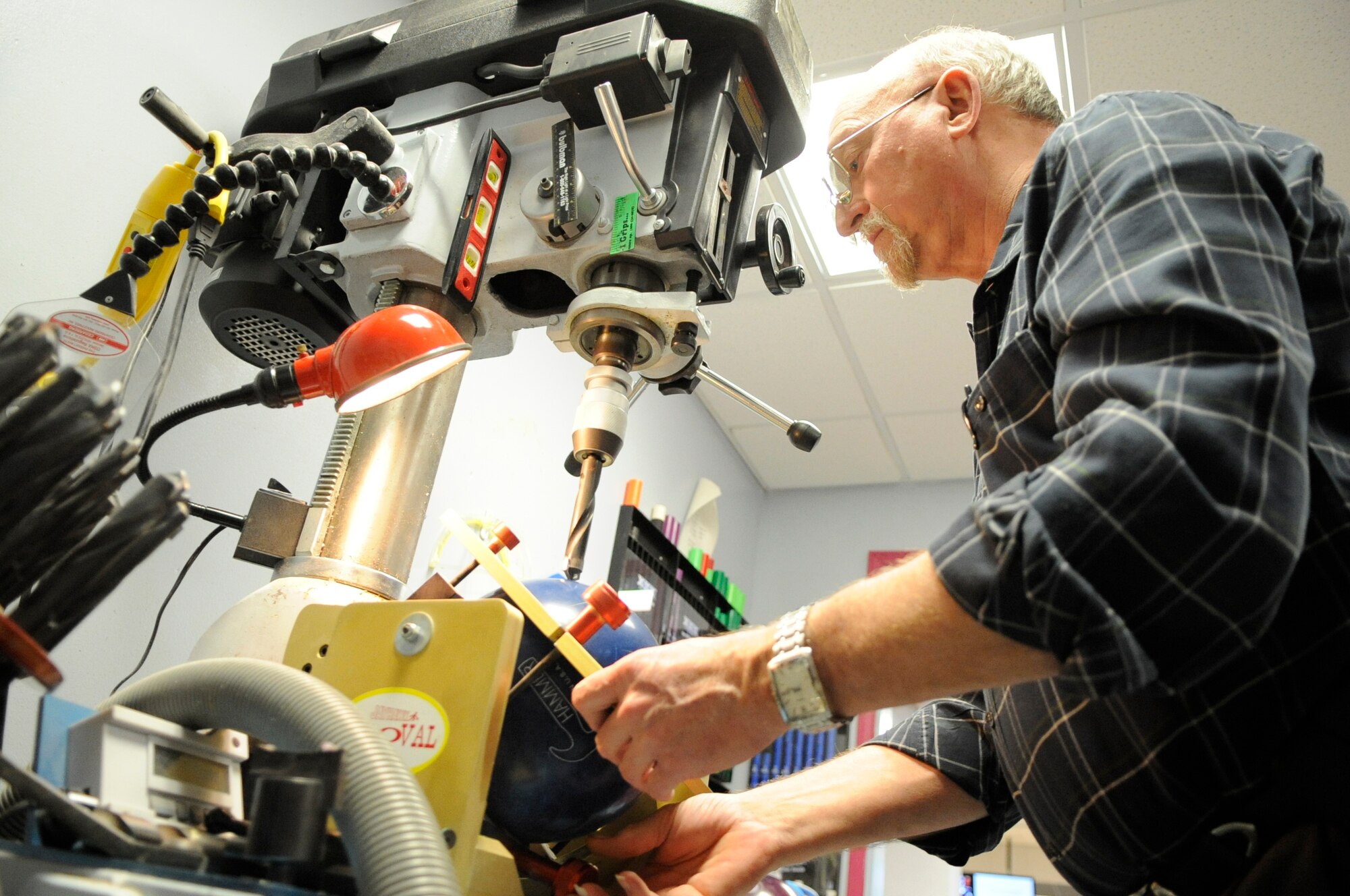 Bobby Choate, Barksdale Bowling Center manager, lines up a bowling ball under a drill at the bowling center on Barksdale Air Force Base, La., Feb. 22. Team Barksdale members can bring their new and used bowling balls to the full-service pro-shop to get custom-drilled holes. (U.S. Air Force photo/Airman 1st Class Andrea F. Liechti)(RELEASED)