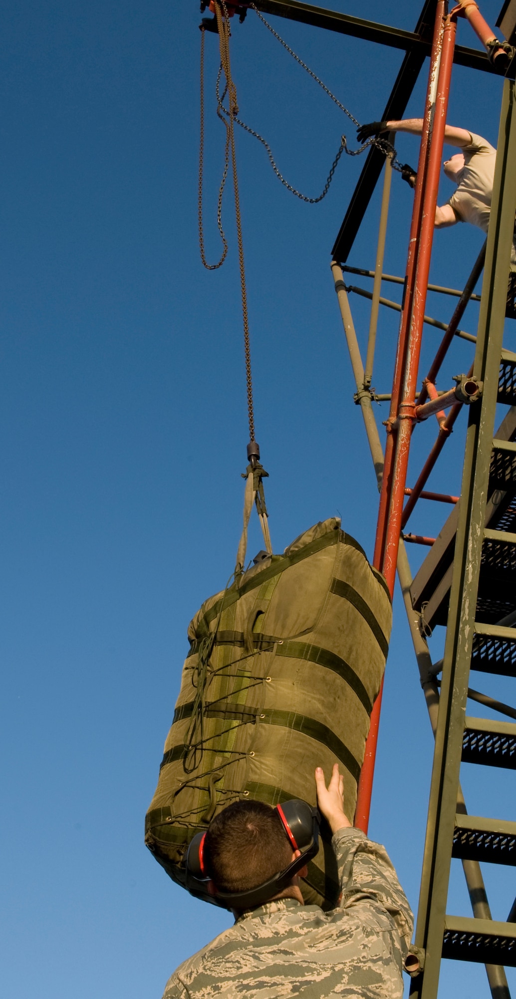 Airman 1st Class Zachary Reph assists Airman 1st Class David Geyer, 11th Aircraft Maintenance Unit, hoist a chute bag on Barksdale Air Force Base, La., Feb. 21. The chute bag holds the large parachute that is used to slow down a rapidly moving B-52H Stratofortress during landing. (U.S. Air Force photo/Airman 1st Class Benjamin Gonsier)(RELEASED) 