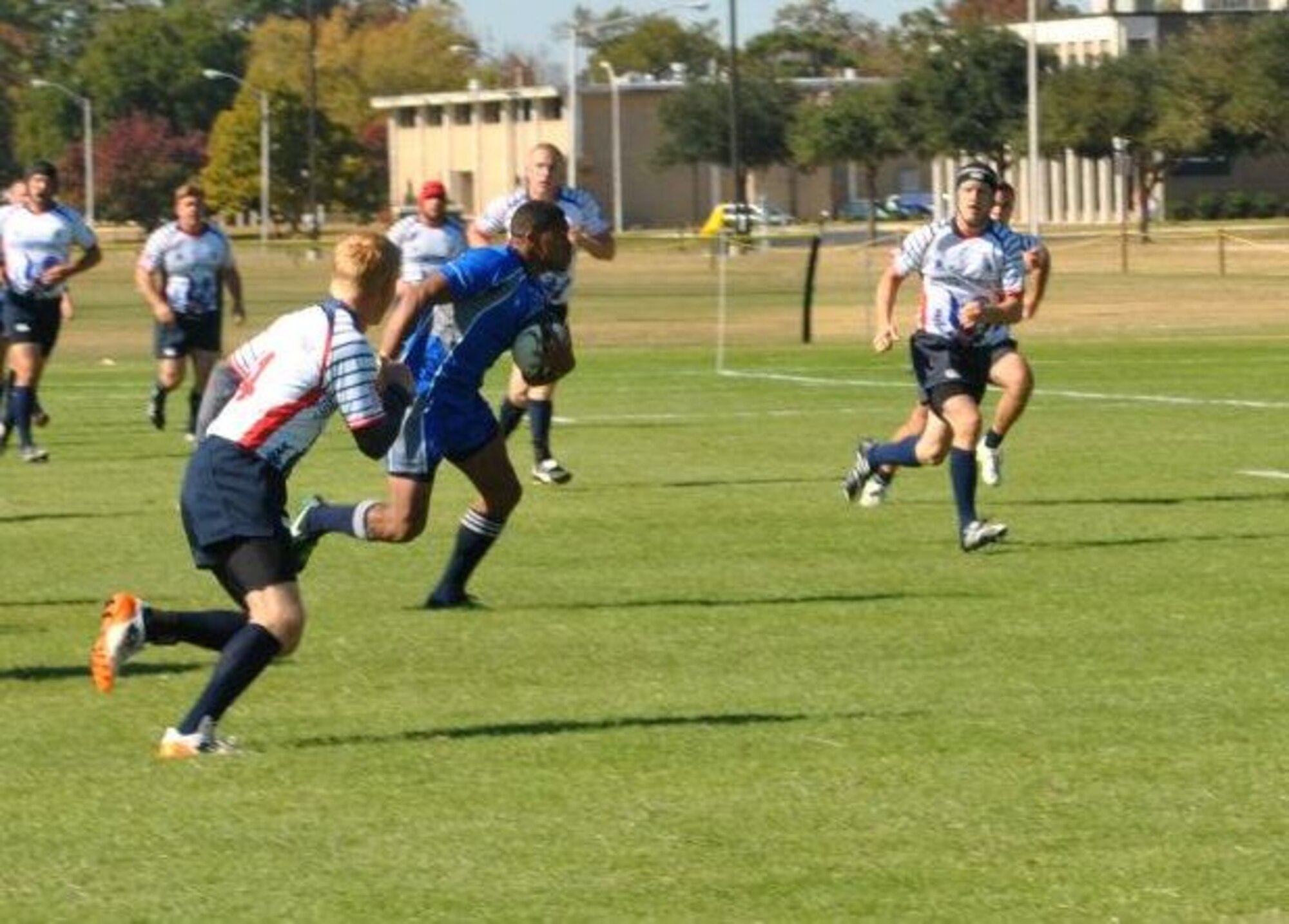 Senior Airman Marcus Satavu, 325th Air Control Squadron pilot simulator, handles the ball in a Rugby match of the Air Force versus the United States Coast Guard. (U.S. Air Force courtesy photo)