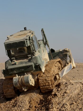 A 3rd Combat Engineer Battalion bulldozer levels the rubble from a recent patrol base reduction, giving the Afghan National Civil Order Police a better view of the area around them, Feb. 23. The battalion demolished or reduced more than a dozen patrol bases in recent months. The Marines with 3rd CEB worked with local Afghan National Security Forces to set the base according to their resources.