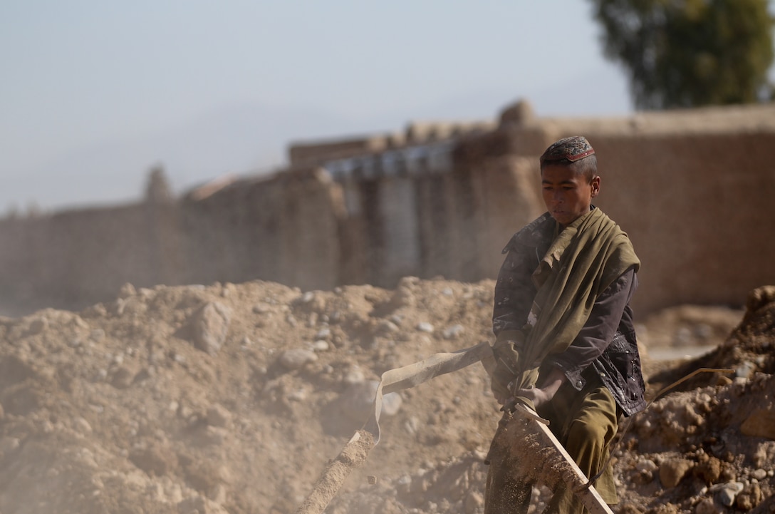 A local Afghan boy pulls debris out of some rubble from the recent patrol base reduction, Feb. 23. Marines with 3rd Combat Engineer Battalion leveled half the patrol base in conjunction with the Afghan National Civil Order Police stationed here. The smaller PB allows for better security for the ANCOP and Marines.