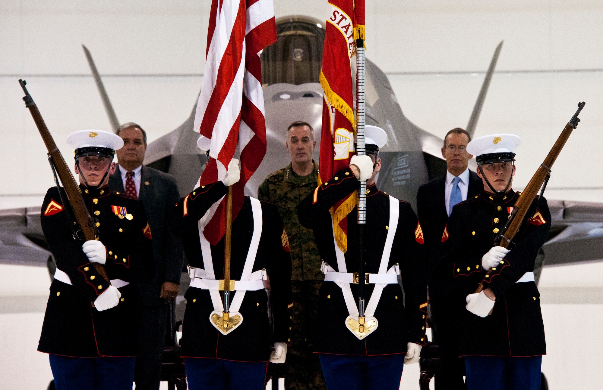 U.S. Congressman Jeff Miller, Assistant Commandant of the Marine Corps. Gen. Joseph Dunford and Chairman and CEO of Lockheed Martin Robert Stevens watch as Marine color guard retire the colors during the Marine Corps F-35B Lightning II roll out ceremony Feb. 24 at Eglin Air Force Base, Fla.  (U.S. Air Force photo/Samuel King Jr.)