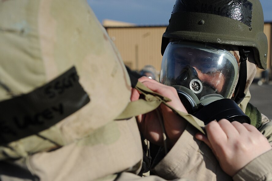 Air Force Staff Sgt. Tyler Haugland, assigned to the 375th Aeromedical Squadron, helps his buddy secure protective overgarments as part of chemical warfare readiness training during an Operational Readiness Exercise held on Scott Air Force Base Feb. 23, 2012. OREs are designed to test the base’s ability to conduct operations in a deployed environment. (U.S. Air Force photo by Master Sgt. Dave DeRemer/Released)

