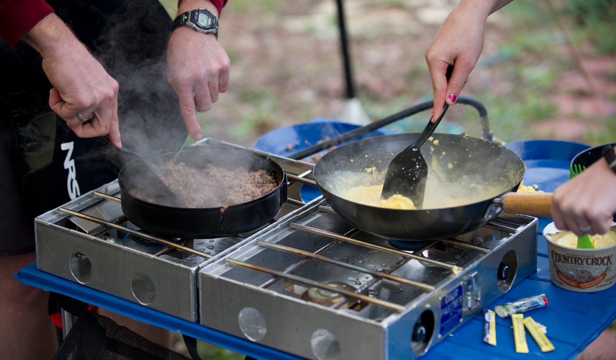 SAN MARCOS, Texas — Participants in the Holloman Outdoor Wingman Program cook breakfast outside at the Power Olympic Outdoor Center as Airmen a spouse and a civilian prepare to fuel their bodies for kayaking through the cold and rain Feb. 19. Airmen participating in the Holloman Outdoor Wingman Program came to here to gain a basic understanding of the principles of kayaking and to learn to apply the same critical thinking skills to everyday life. Each Airman spouse and civilian walked away with a better understanding of both how to manage themselves on a white-water rapid and how to cope through the stress of work in a healthy way. (U.S. Air Force Photo by Airman 1st Class Daniel E. Liddicoet/Released)