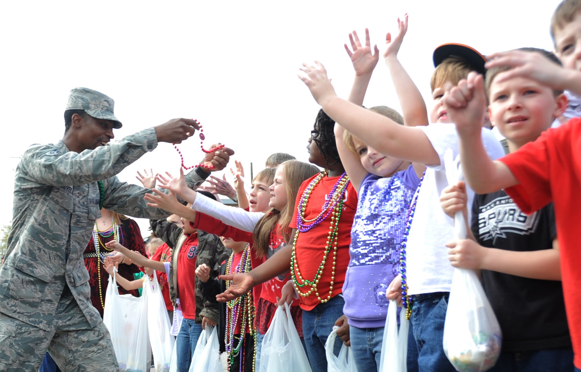 Airman 1st Class Kevin Lovelace, 335th Training Squadron, passes beads to students during the Jeff Davis Elementary School Mardi Gras parade in Biloxi, Miss., Feb. 17, 2012.  (U.S. Air Force photo by Kemberly Groue)