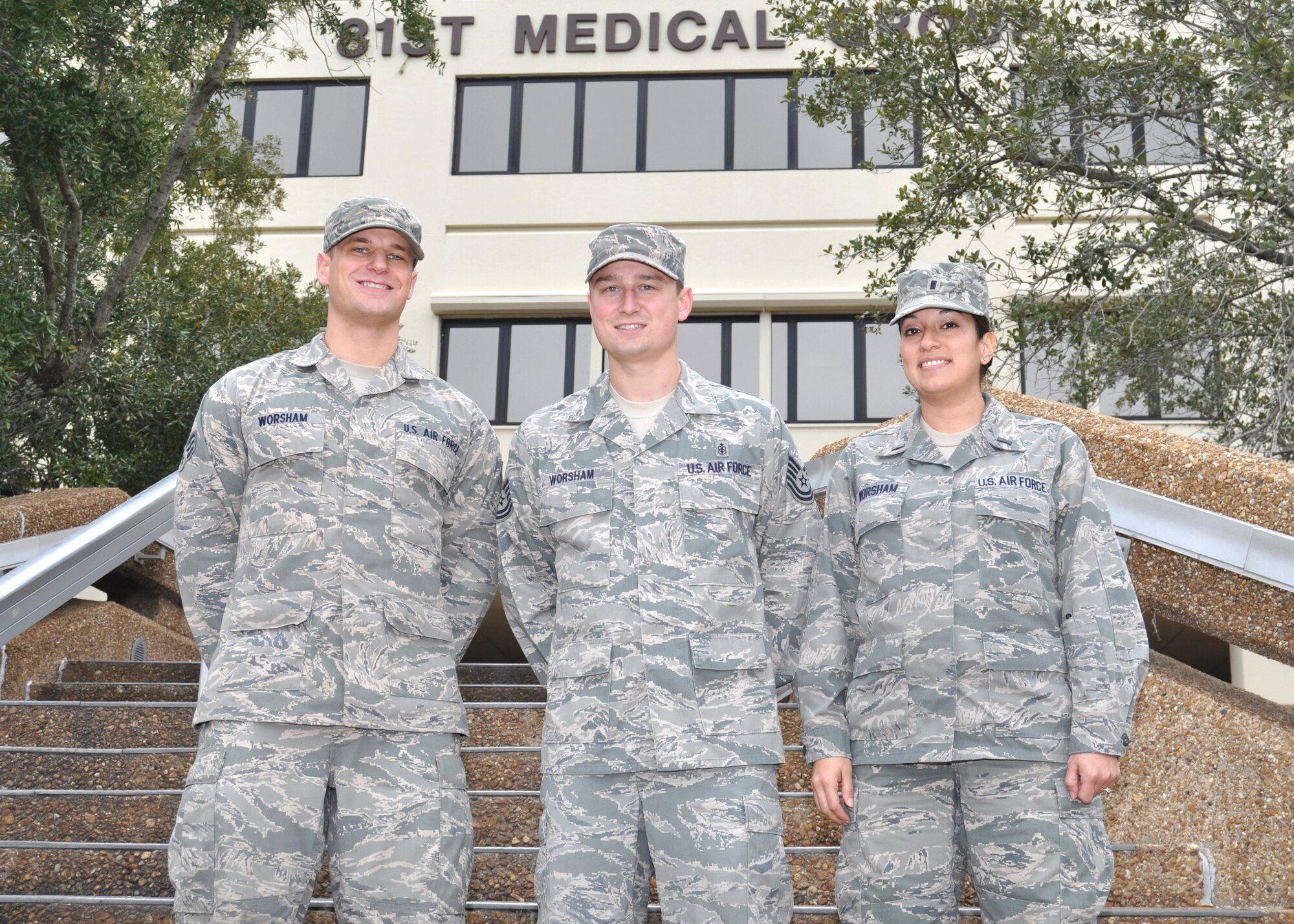 Senior Airman Daniel Worsham, 81st Medical Operations Squadron emergency medical technician; Tech. Sgt. Matthew Worsham, 81st MDOS noncommissioned officer in charge of the cardiac cath lab and a respiratory therapist with the critical care air transport team; and 1st Lt. Angelica Worsham, 81st MDOS physician assistant in the family health clinic, pose for a family photo in front of the Keesler Hospital at Keesler Air Force Base, Miss.  Airman Worsham and Sergeant Worsham are brothers.  Sergeant Worsham is married to Lieutenant Worsham.  (U.S. Air Force photo by Steve Pivnick)