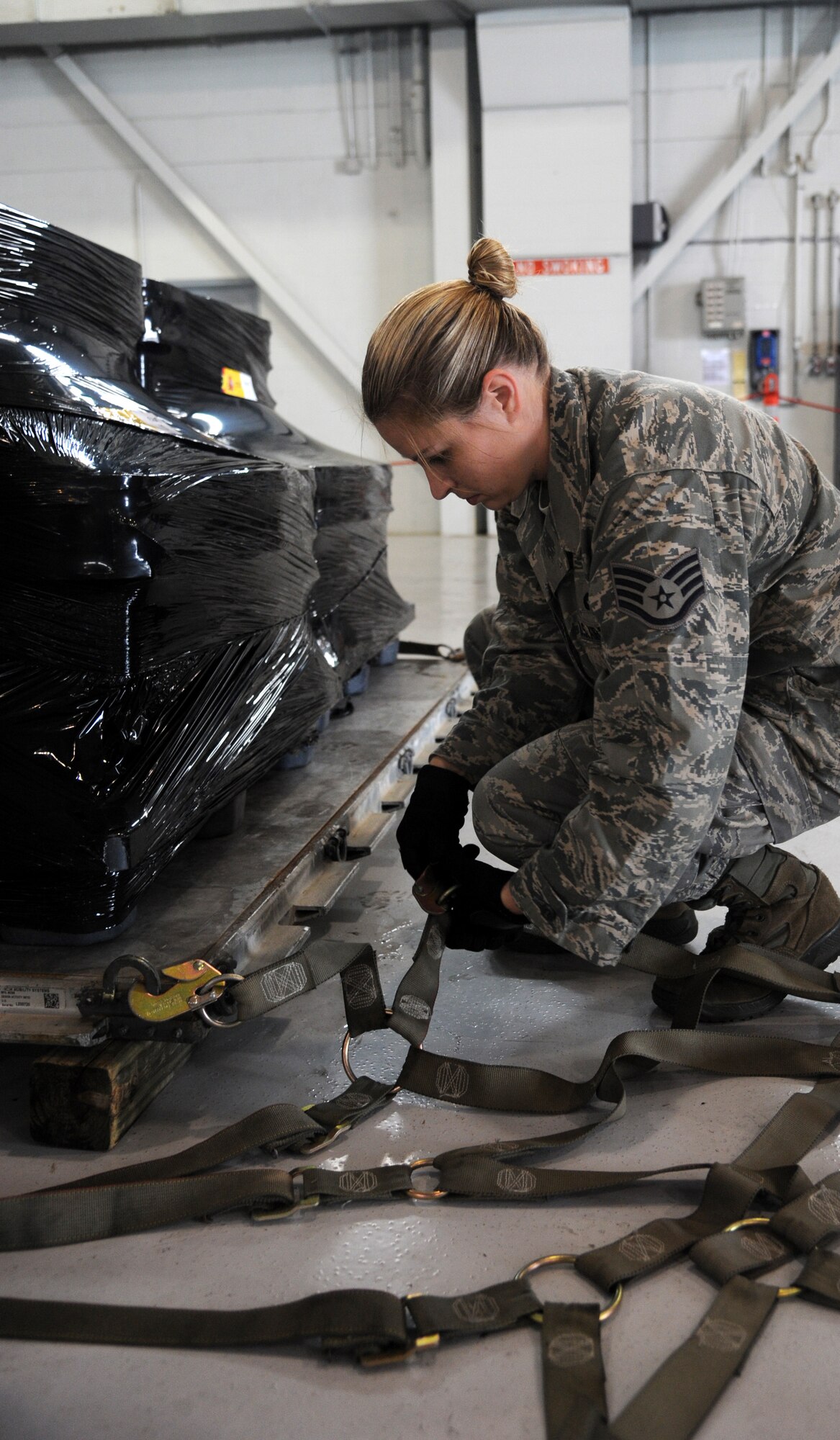 Staff Sgt. Rachael McCray, 6th Logistics Readiness Squadron Mobility Training Instructor, connects a cargo net to a pallet of Spanish coins to be loaded on a Spanish C-130 at MacDill Air Force Base, Fla., Feb. 23, 2012. The coins, which were lost at sea in the 19th century, are being palletized in preparation for their long awaited return back to Spain. (U. S. Air Force photo by Airman Basic David Tracy)  