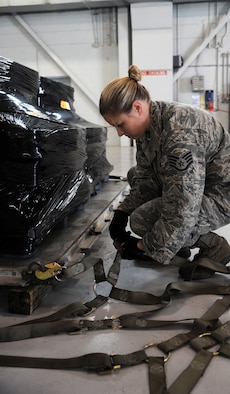 Staff Sgt. Rachael McCray, 6th Logistics Readiness Squadron Mobility Training Instructor, connects a cargo net to a pallet of Spanish coins to be loaded on a Spanish C-130 at MacDill Air Force Base, Fla., Feb. 23, 2012. The coins, which were lost at sea in the 19th century, are being palletized in preparation for their long awaited return to Spain. (U. S. Air Force photo/Airman Basic David Tracy)