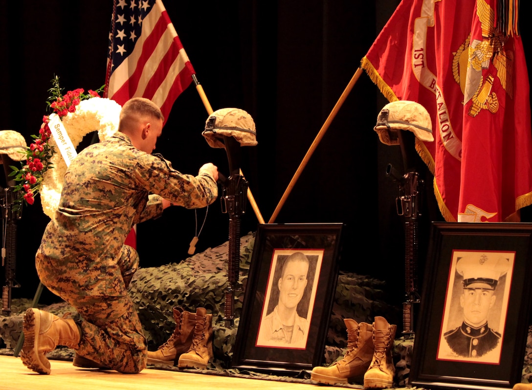 A Marine with 1st Battalion, 6th Marine Regiment, 2nd Marine Division places a set of identification tags on the grip of the memorial stand of Lance Cpl. Franklin N. Watson, during the 1st Bn., 6th Marines, memorial service held in honor of eight of the battalion's fallen heroes in the base theater aboard Marine Corps Base Camp Lejeune, N.C., Feb. 24.