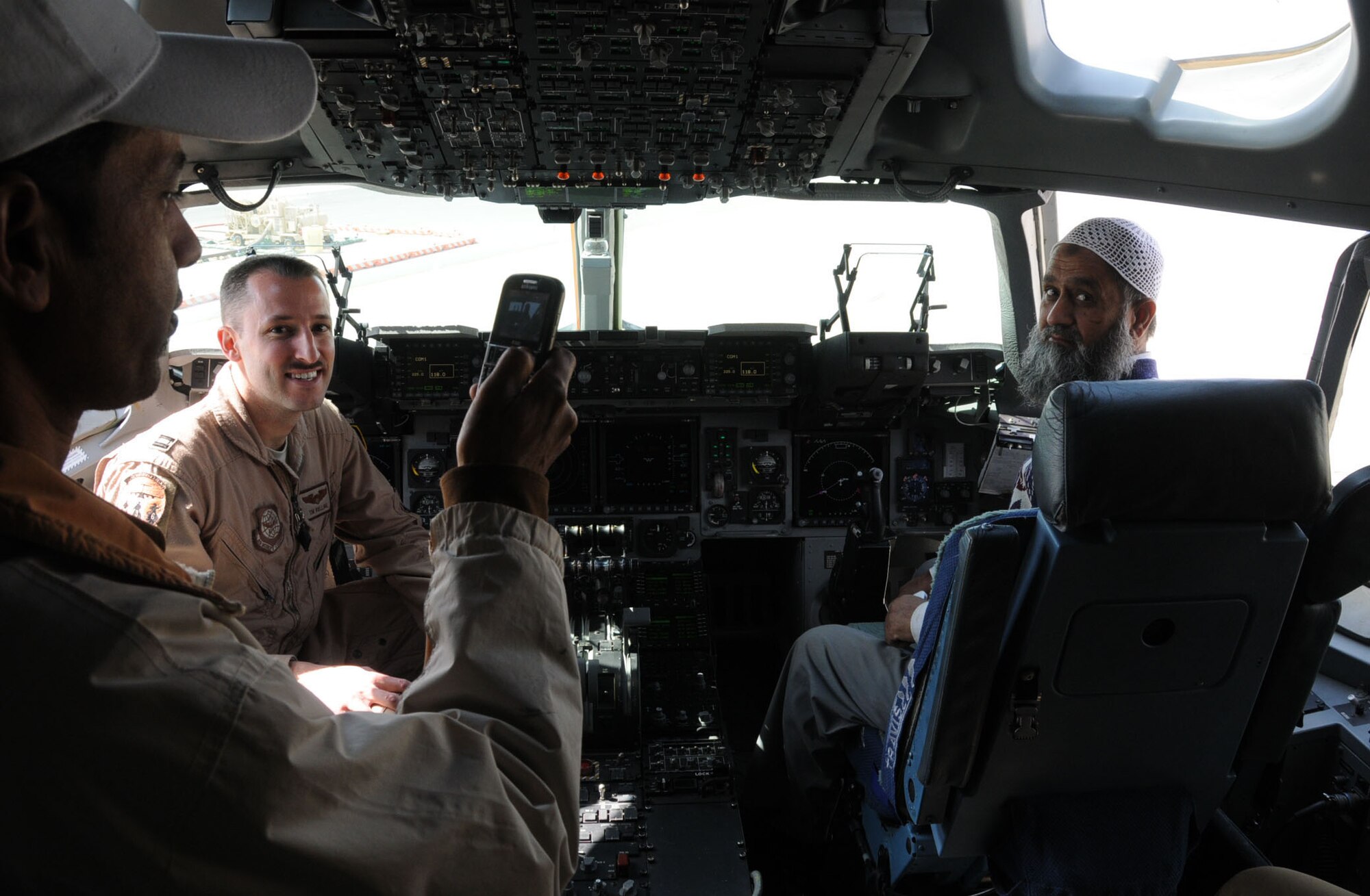 U.S. Air Force Capt. Tim Rolling, member of the 386th Expeditionary Operations Group and native of Dallas, Texas, shows host nation civilians the cockpit of a Boeing C-17 Globemaster III at an undisclosed location, Southwest Asia, Feb. 23, 2012. Rolling, deployed from the 6th Airlift Squadron, Joint Base McGuire-Dix-Lakehurst, N.J., was part of a number of U.S. and host nation military members that displayed their respective aircraft, vehicles and cooperation to host nation military members and their families as well as fellow U.S. military members during an open house. (U.S. Air Force photo by Staff Sgt. James Lieth/Released)
