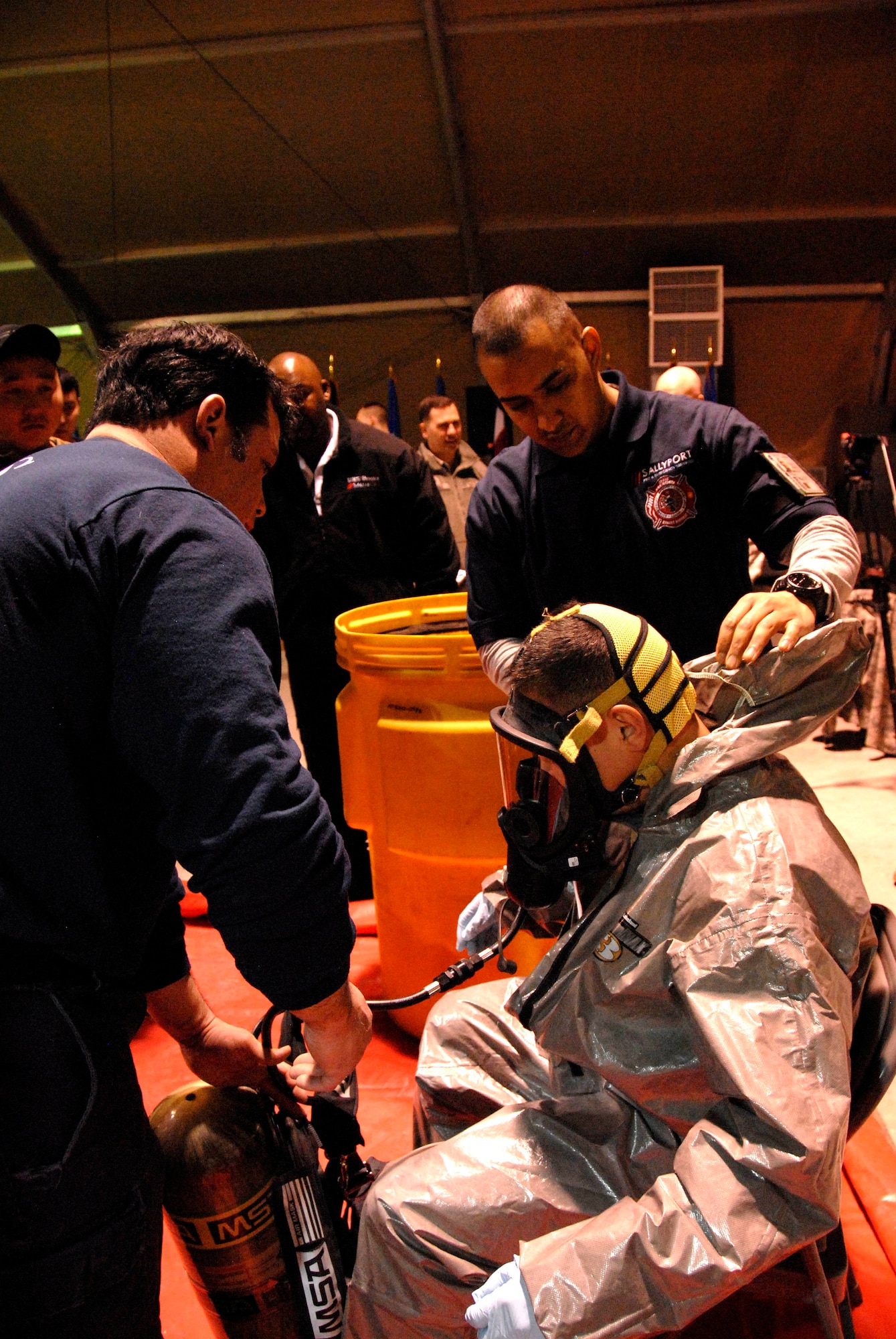Mark Williams (left) and Joshua Nightingale, Transit Center at Manas Fire Department crew chiefs, assist a Kyrgyz Ministry of Defense member with his gear during an information exchange at the Transit Center, Feb. 22, 2012. Emergency responders from the Kyrgyz Ministries of Emergency Services, Interior and Defense visited the Transit Center to exchange information on explosive ordnance disposal and chemical, biological, radiological, nuclear and high-yield explosives response. The military-to-military event was part of a continuing partnership information exchange that familiarizes Kyrgyz experts with U.S. Air Force CBRNE and EOD tactics, techniques and procedures. (U.S. Air Force photo/Senior Airman Lynsie Nichols)
