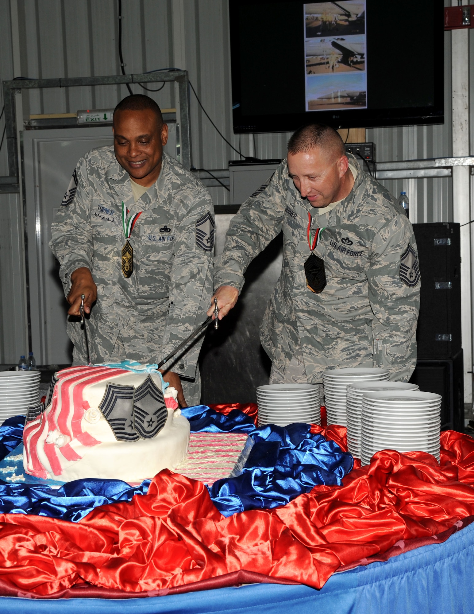 SOUTHWEST ASIA - Senior Master Sgts. Paul Turner and Todd Joiner cut a cake Feb. 24, 2012. The 380th Air Expeditionary Wing celebrated their promotion to chief master sergeant with a recognition ceremony. (U.S. Air Force photo/Tech. Sgt. Arian Nead)
