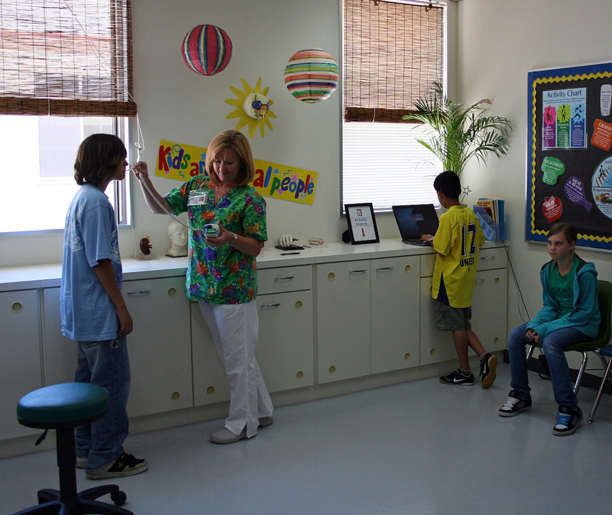 Holly Gouldman, a school nurse with the Department of Defense Education Activity Pacific, checks a student’s temperature while other students sign in at the Ryukyu Middle School nurse’s office on Kadena Air Base, Japan, Feb. 27, 2012. Gouldman, who has been a nurse with DoDEA Pacific schools for 12 years, was recently selected as the Overseas School Health Nurses Association 2012 School Nurse of the Year. (Courtesy photo/Released) 