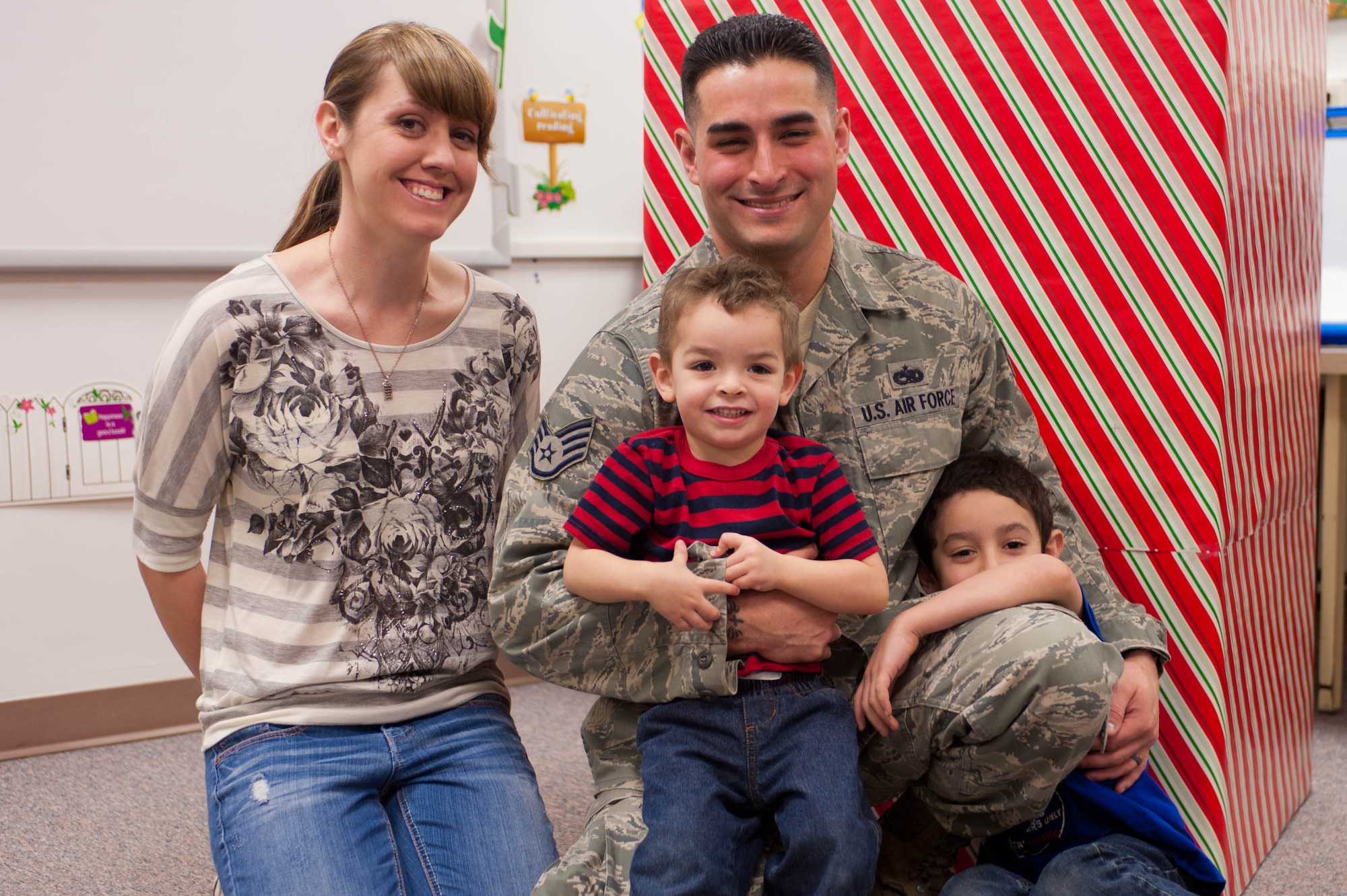 Staff Sgt. George Munoz, 28th Munitions Squadron weapon systems craftsman, catches up with his family after surprising his two sons Dylan, 5, and Eric, 2, at the Robbinsdale Elementary School library in Rapid City, S.D., Feb. 17, 2012. Munoz returned home after a year-long assignment to Kunsan Air Base, South Korea. (U.S. Air Force photo by Airman 1st Class Zachary Hada/Released)