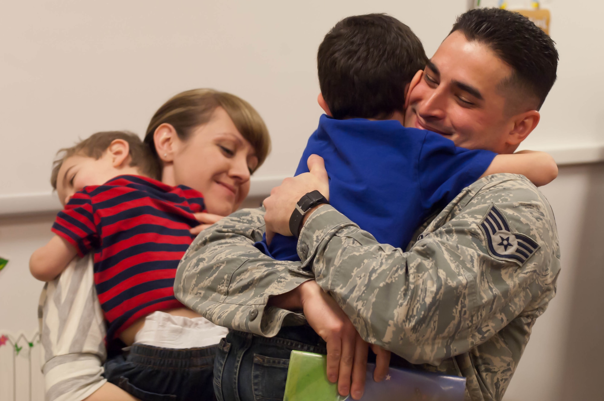 Staff Sgt. George Munoz, 28th Munitions Squadron weapon systems craftsman, and his wife Christan, embrace their children Dylan, 5, and Eric, 2, at the Robbinsdale Elementary School library in Rapid City, S.D., Feb. 17, 2012. Munoz reunited with his family after a year-long assignment from Kunsan Air Base, South Korea. (U.S. Air Force photo by Airman 1st Class Zachary Hada/Released)