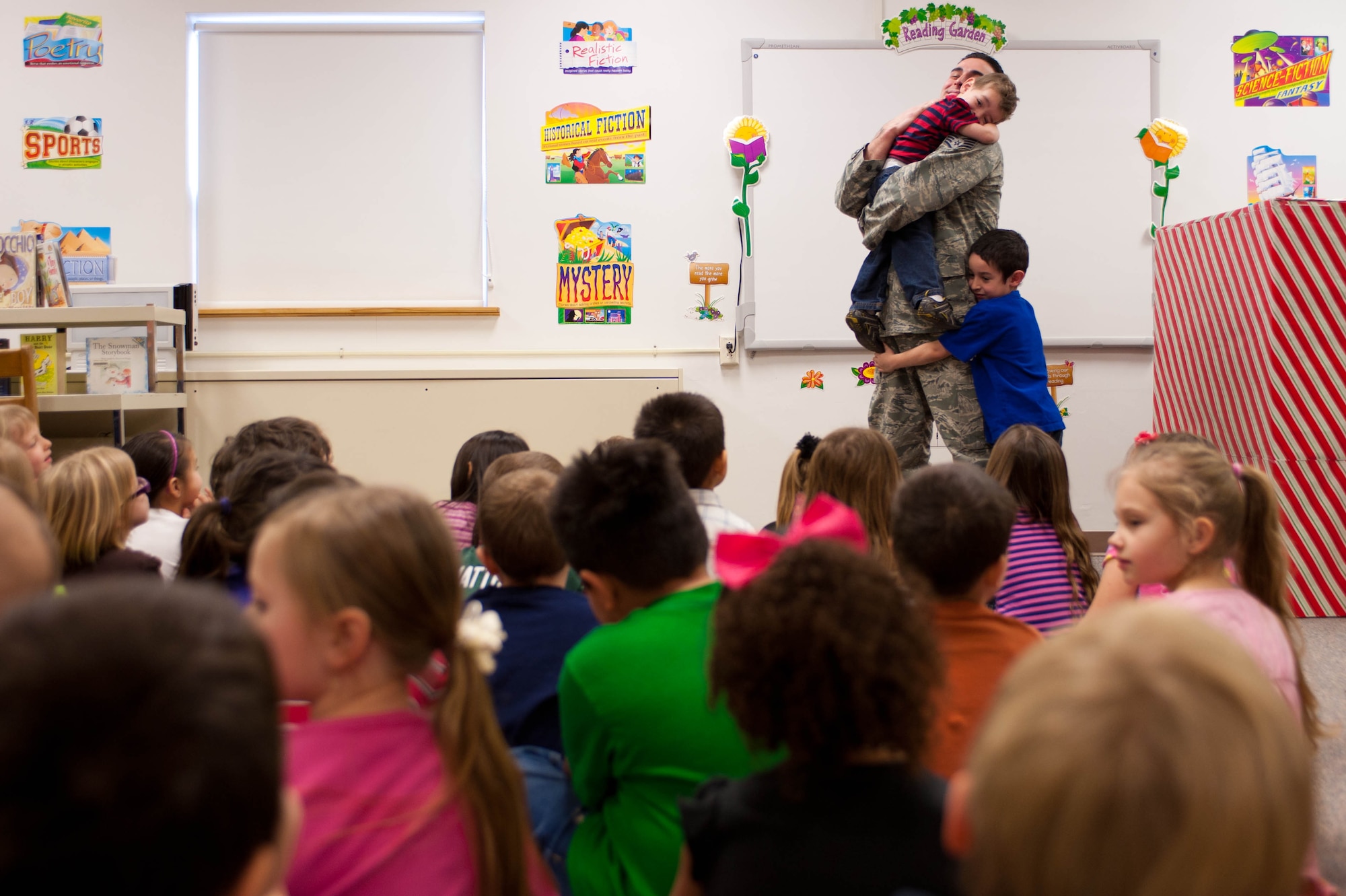 Staff Sgt. George Munoz, 28th Munitions Squadron weapon systems craftsman, hugs his two sons Dylan, 5, and Eric, 2, at the Robbinsdale Elementary School library in Rapid City, S.D., Feb. 17, 2012. The whole kindergarten class was in attendance to see Munoz surprise his son, who he had not seen in a year due to his assignment to Kunsan Air Base, South Korea. (U.S. Air Force photo by Airman 1st Class Zachary Hada/Released)