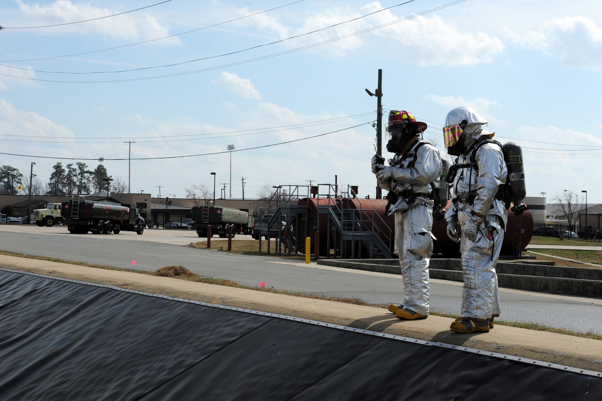 U.S. Air Force Staff Sgt. Rodger Kemp and Senior Airman Kyle Vega examine a fuel tank during a fuel spill exercise on Seymour Johnson Air Force Base, N.C., Feb. 23, 2012. During the fuel spill exerise, Airmen responded to a fuel tank that leaked 750,000 gallons of simulated JP-8 which spilled onto the ground and into water drains. Kemp and Vega are 4th Civil Engineer Squadron fire emergency services flight firefighters. Kemp hails from Chicago, and Vega is a native of Atlanta. (U.S. Air Force photo/Airman 1st Class Mariah Tolbert/Released)