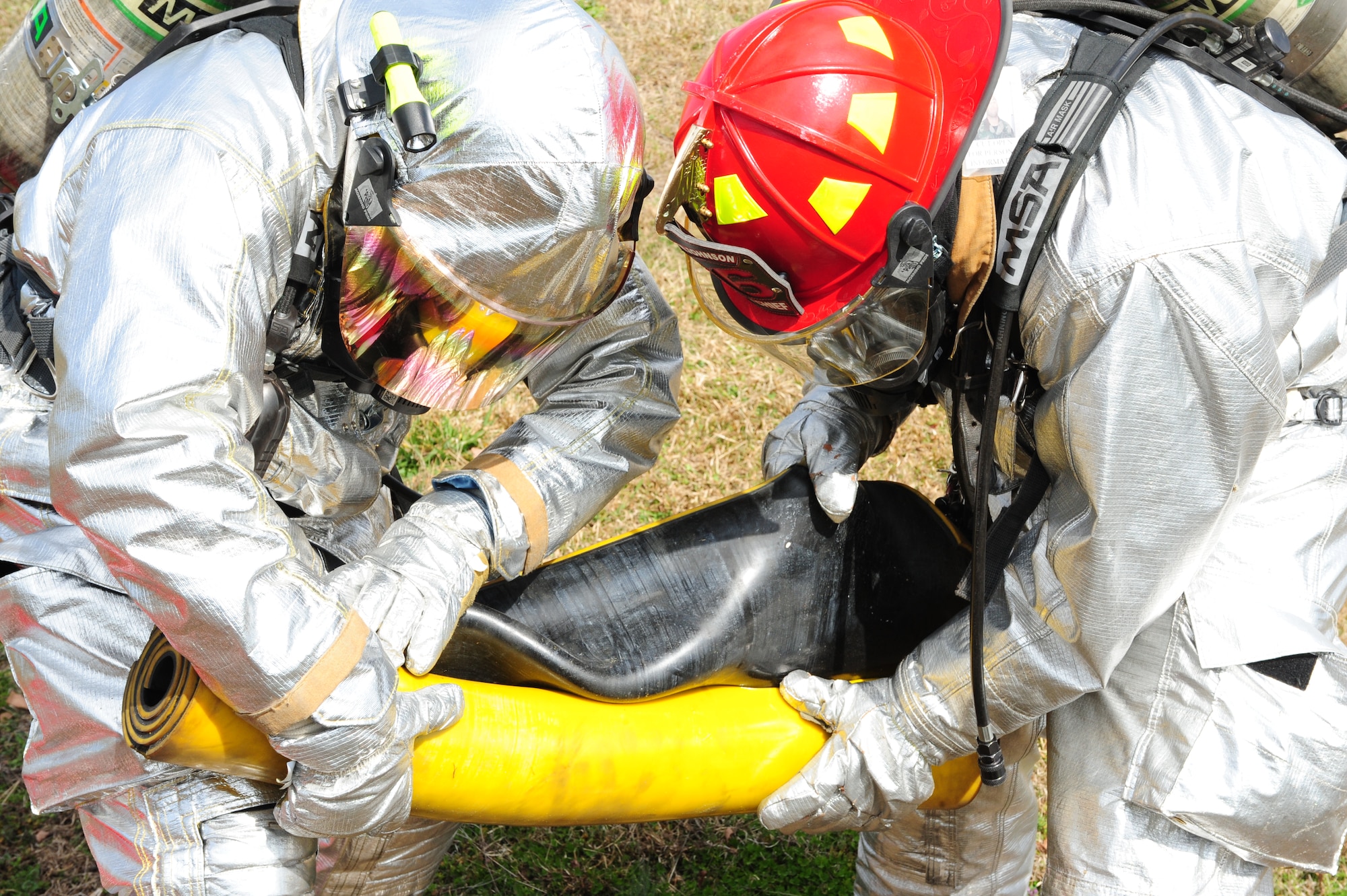 U.S. Air Force Staff Sgt. Rodger Kemp and Senior Airmen Kyle Vega unroll a rubber drain cover during a fuel spill exercise on Seymour Johnson Air Force Base, N.C., Feb. 23, 2012. The rubber drain cover prevents the majority of oil from flowing into the drains and affecting the water supply on and off base. Kemp and Vega are 4th Civil Engineer Squadron fire emergency services flight firefighters. Kemp hails from Chicago, and Vega is a native of Atlanta. (U.S. Air Force photo/Airman 1st Class Mariah Tolbert/Released) 