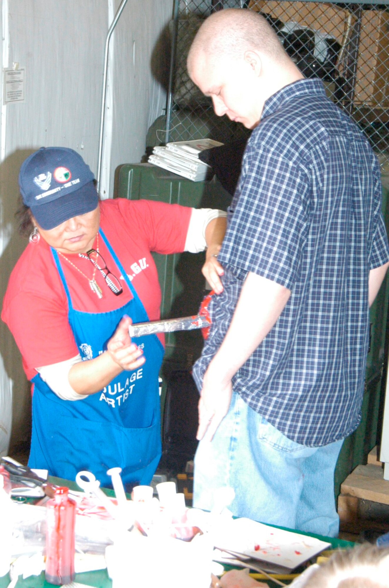 Moulage specialist Sunny Schones, 72nd Medical Group, fabricates a simulated stomach wound for Michael Wilson, a computer scientist in the 558th Software Maintenance Group, who portrayed one of the tornado victims during the Feb. 15 emergency preparedness exercise at Tinker. (Air Force photo by Mike Ray)