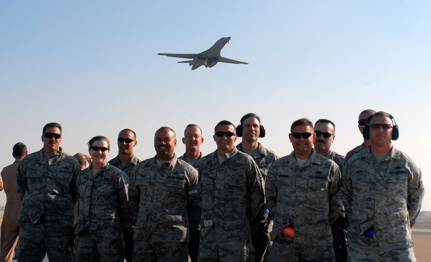 Members from the 9th Expeditionary Aircraft Maintenance Unit pose for a group photo as a B-1 Bomber flies overhead for the airframe’s 10,000th combat mission Feb. 26, 2012. The B-1, or “Bone” as it is affectionately known, performed its first combat mission in December 1998 during Operation Desert Fox. Several upgrades have been made to the B-1 over the last 30 years in order to make it a highly versatile, multi-mission weapon system. (Courtesy photo)