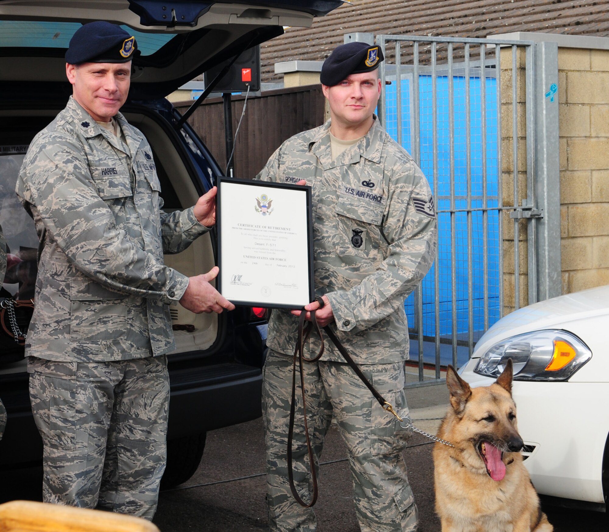 RAF MILDENHALL, England – Lt. Col. David Harris, 100th Security Forces Squadron commander, presents a Certificate of Appreciation – signed by the Chief of Staff of the Air Force and Col. Kulas, 100th Air Refueling Wing commander – to 100th SFS Military Working Dog handler, Staff Sgt. Samuel Giordano, for MWD Desant who retired from service here Feb. 24, 2012. Desant finished eight years of service with the U.S. Air Force at RAF Mildenhall, amassing 9,000 working hours – 2,500 of which were explosive detection. (U.S. Air Force photo/Karen Abeyasekere)