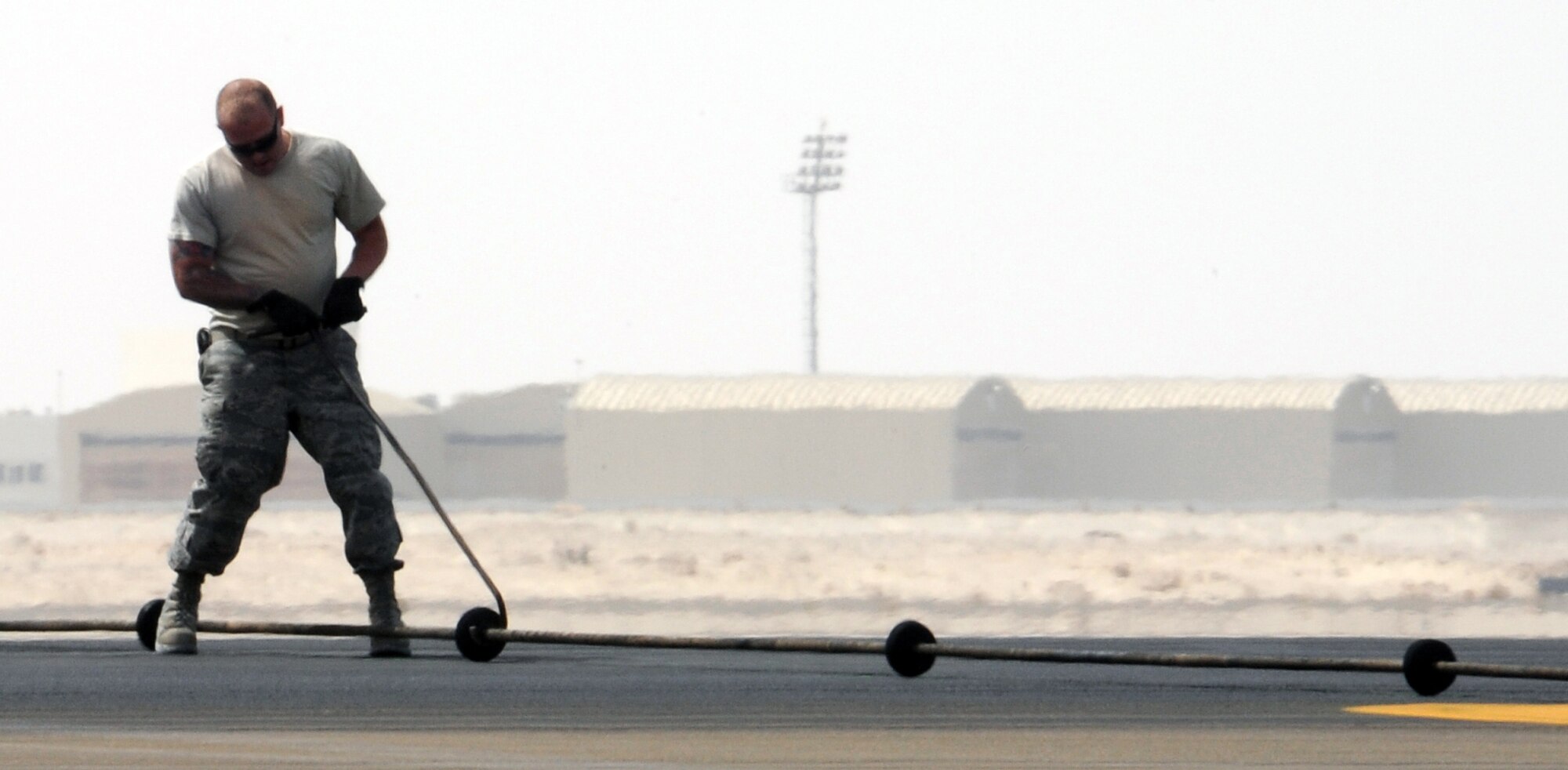 SOUTHWEST ASIA - An Airman helps install a new arresting barrier system for the 380th Air Expeditionary Wing Feb. 25, 2012. The system consists of a cable stretched across a flightline and hooked up to motorized retractors on either side. If a fighter has some type of malfunction that affects its brakes, pilots can use the arresting cable to stop safely. This was the certification test for a new system, which has to be replaced every 10 years. (U.S. Air Force photo/Staff Sgt. J.G. Buzanowski)
