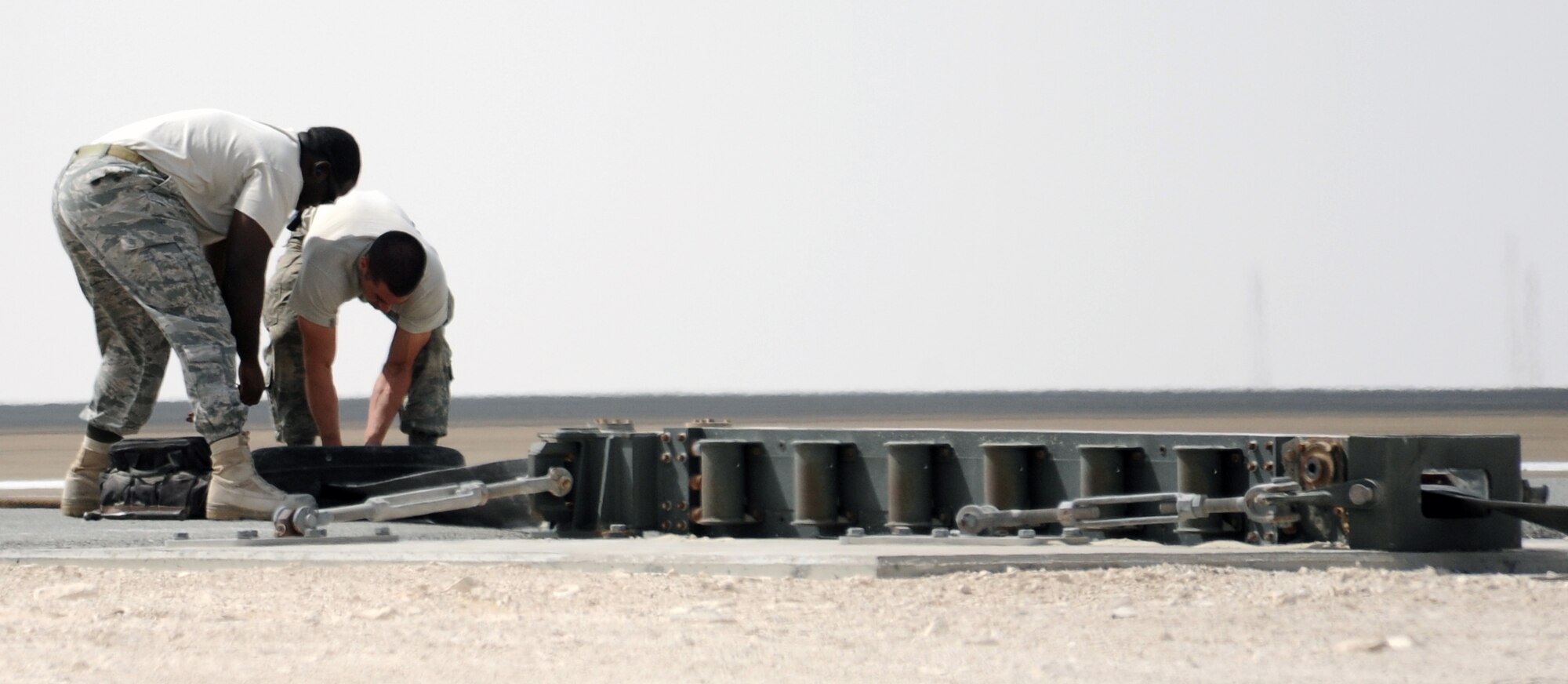 SOUTHWEST ASIA - Airmen install a new arresting barrier system for the 380th Air Expeditionary Wing Feb. 25, 2012. The system consists of a cable stretched across a flightline and hooked up to motorized retractors on either side. If a fighter has some type of malfunction that affects its brakes, pilots can use the arresting cable to stop safely. This was the certification test for a new system, which has to be replaced every 10 years. (U.S. Air Force photo/Staff Sgt. J.G. Buzanowski)