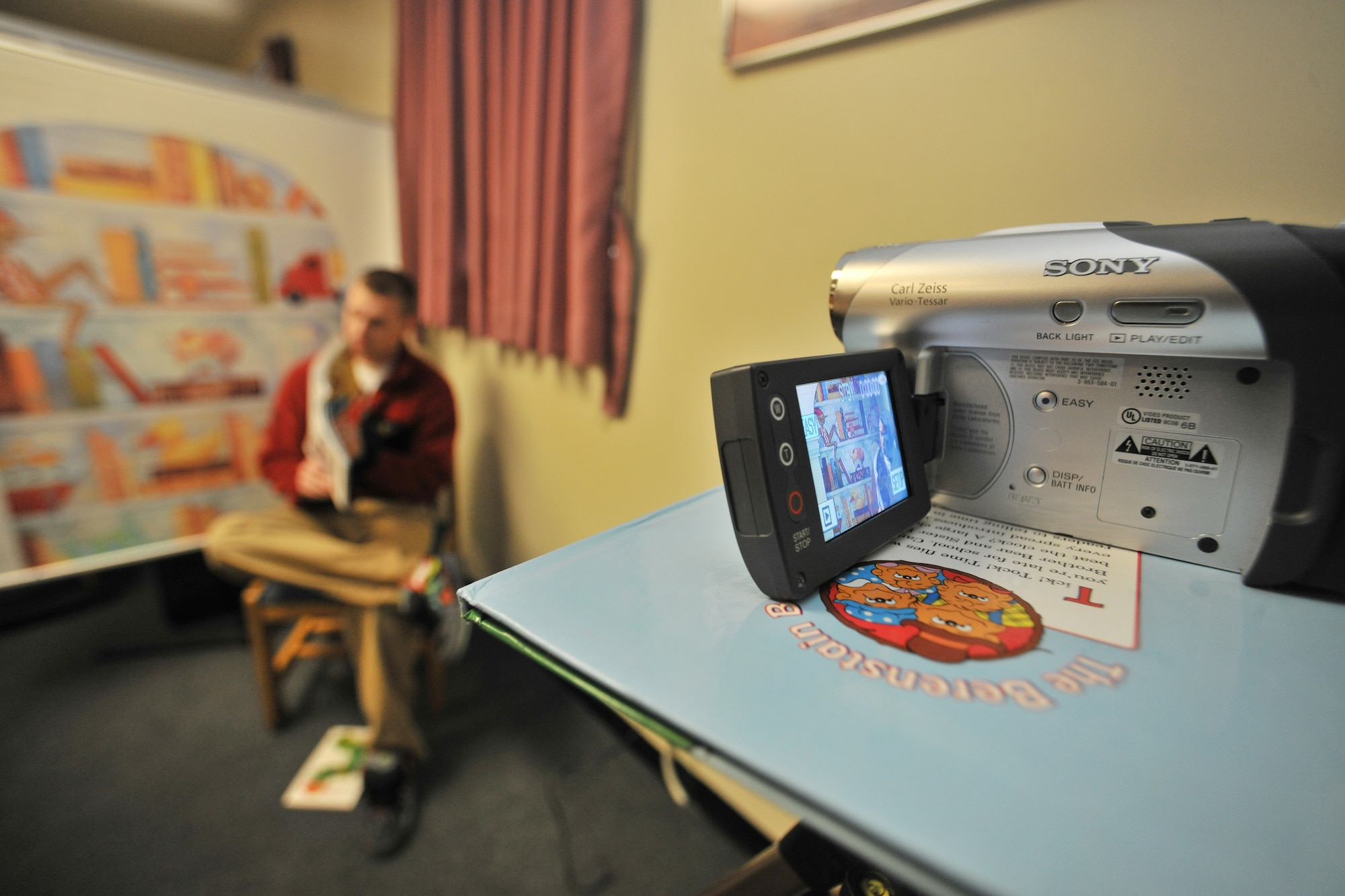 Staff Sgt. James Blaylock, 421st Expeditionary Fighter Squadron aircrew flight equipment, reads a book aloud and shows the photos to the camera while being recorded on DVD to send to his family at Kunsan Air Base, Republic of Korea, Feb. 21, 2012. United Through Reading is a USO program that offers servicemembers the chance to read a book aloud while being recorded on DVD for their child. (U.S. Air Force photo by Senior Airman Brittany Y. Auld/Released)