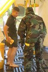 Lorton, VA - A Marine with Decontamination Platoon, Initial Response Force "A," React Company, Chemical Biological Incident Response Force, demonstrates how to self decontaminate to a “victim” during their certification exercise 14 June.