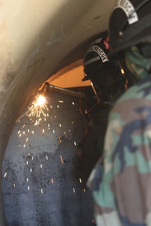 Lorton, VA - Sgt. Mark A Bentley, Materials Chief, Technical Rescue Platoon, Initial Response Force "A," React Company, Chemical Biological Incident Response Force, cuts through a plate of steel, during a training exercise, to gain access to a "victim" trapped in the debris. (Released)