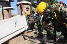 Lorton, VA - Sgt. Steven M. baduske with Victim Extracation Platoon, Initial Response Force "A," React Company, Chemical Biological Incident Response Force, assists Marines from the Tecnical Rescue Platoon, free a “victim” from under a cement block during their certification exercise 14 June.
