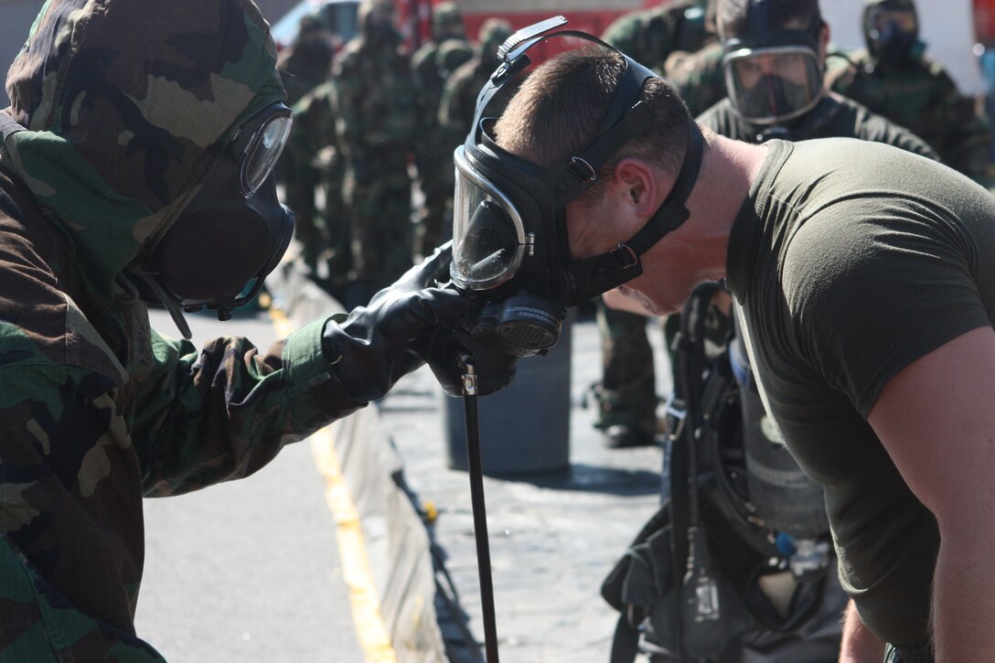 RANDALL’S ISLAND, N.Y. – A Marine with Decontamination Platoon, Initial Response Force B, Chemical Biological Incident Response Force takes off a fellow Marine's respirator gas mask as he passes through the decontamination line during training with the New York City Fire Department’s Special Operations Command fire fighters. Marines and sailors of CBIRF have trained with FDNY since July of 2000. Deputy Chief Raymond M. Downey, of FDNY’s SOC, helped CBIRF develop their technical rescue program before he later died on 9/11 in the World Trade Center towers.