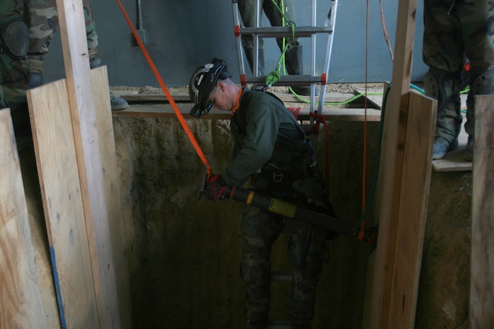 Cpl David Pratt, a technical rescue Marine with Chemical Biological Incident Response Force’s Technical Rescue Platoon, adjusts a strut to stabilize the walls of a trench before they enter to extract two “victims” from a simulated collapse during the joint 72-hour technical rescue training operation with the 911th U.S. Army Technical Rescue Engineer Company at Downey Responder Training Facility. According to Mr. Patrick Higgins, lead CBRNE instructor for CBIRF, a trench rescue is probably one of the most common and most dangerous rescues due to the frequency of trenches being done for installing or repairing of utilities and the many variables involved with a trench.