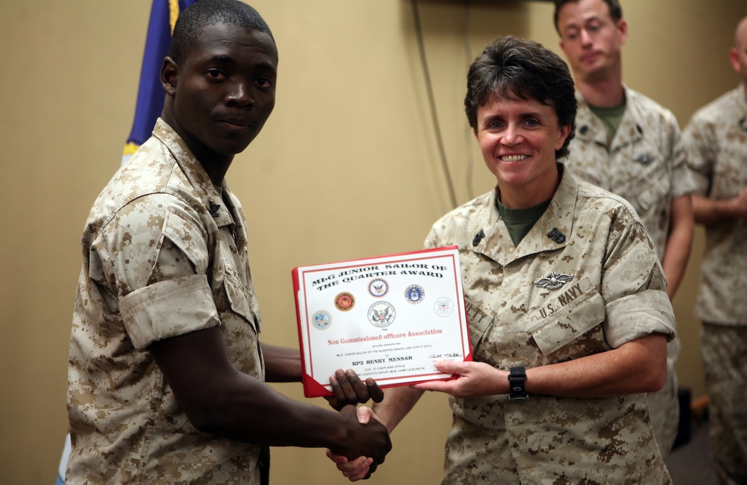 Petty Officer 2nd Class Henry Mensah, a religious program specialist with 2nd Marine Logistics Group, poses for a photo with Master Chief Kelly Mcnulty, command master chief for 2nd MLG, during an award ceremony at the 2nd MLG Chaplain Center aboard Camp Lejeune, N.C., September 19, 2011. Mensah received the Junior Sailor of the Quarter Award for his outstanding work and determination. (U.S. Marine Corps photo by Pfc. Franklin E. Mercado)