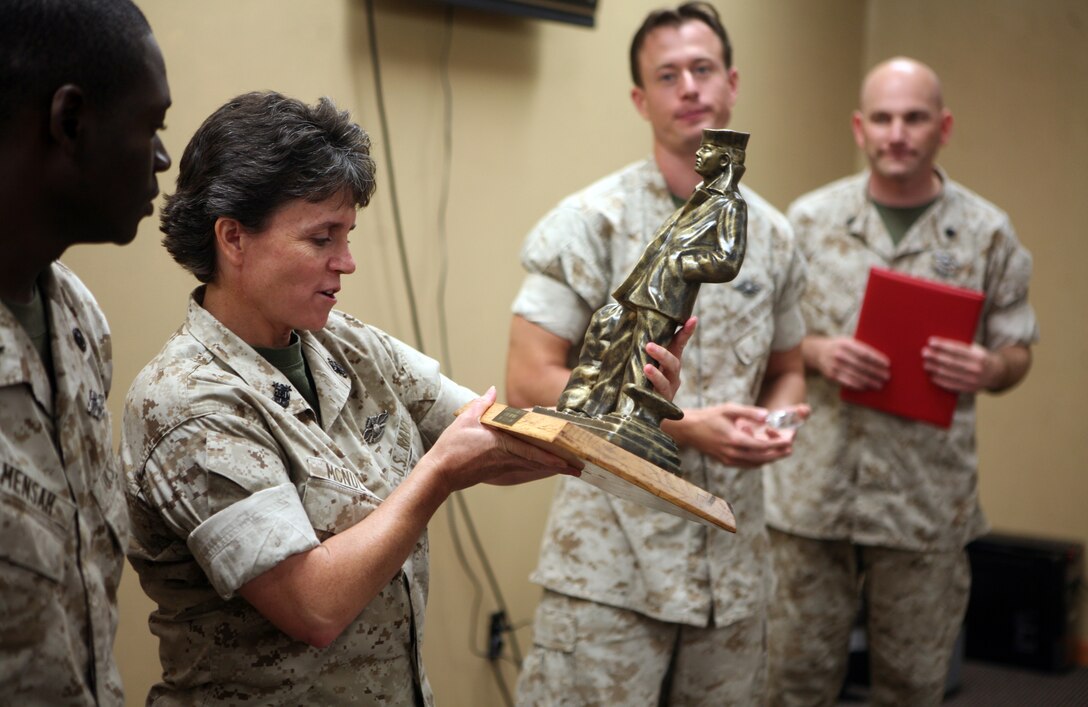 Master Chief Kelly Mcnutly, command master chief for 2nd Marine Logistics Group, reads the plaque on an award during a ceremony at the 2nd MLG Chaplain Center aboard Camp Lejeune, N.C., for Petty Officer 2nd Class Henry Mensah, a religious program specialist with 2nd MLG, September 19, 2011. Mensah received the Junior Sailor of the Quarter Award for his outstanding work and determination.  (U.S. Marine Corps photo by Pfc. Franklin E. Mercado)