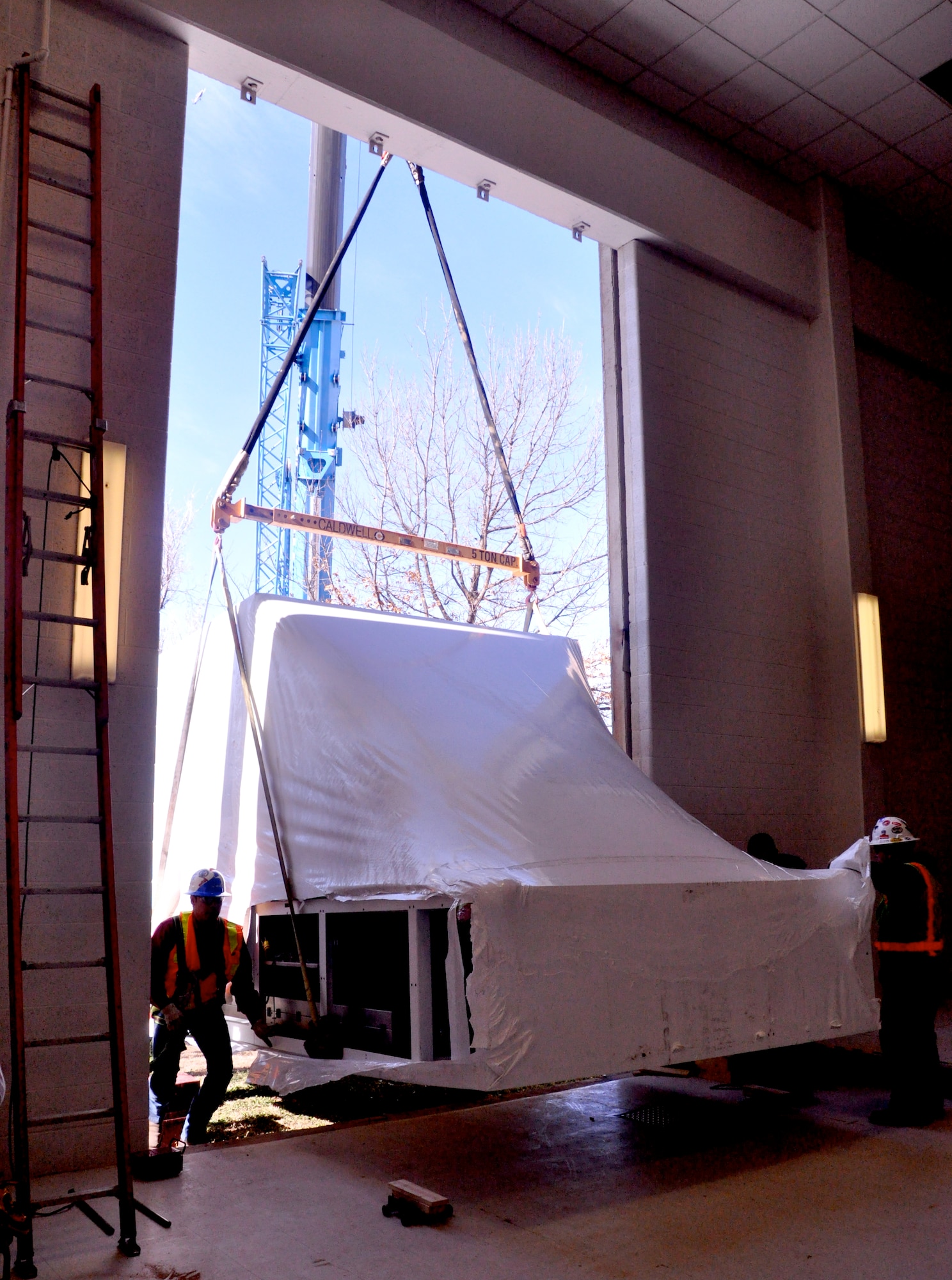 A five-ton section of the new T-1A Jayhawk flight simulator is lifted through the side of the 71st Operations Group building Feb. 22 at Vance Air Force Base, Okla., by a crane from Taylor Crane Rigging in Coffeyville, Kan. The simulator is the second Vance has received from L-3. (U.S. Air Force photo/ Airman 1st Class Frank John Casciotta)