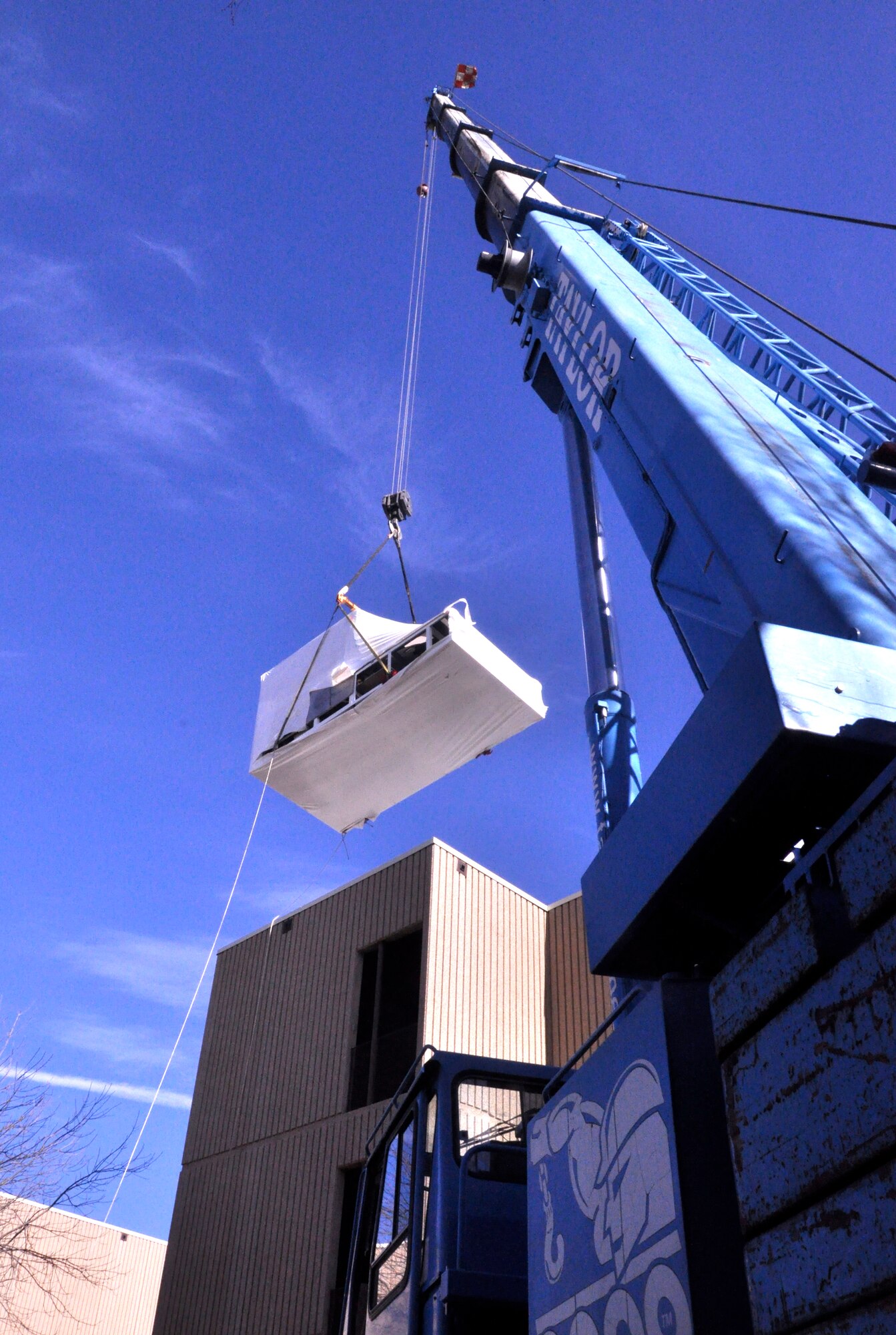 A new T-1A Jayhawk flight simulator is lifted over the 71st Operations Group building Feb. 22 at Vance Air Force Base, Okla., by a crane from Taylor Crane Rigging in Coffeyville, Kan. The simulator is the second Vance has received from the L-3 Communications company. (U.S. Air Force photo/ Airman 1st Class Frank John Casciotta)
