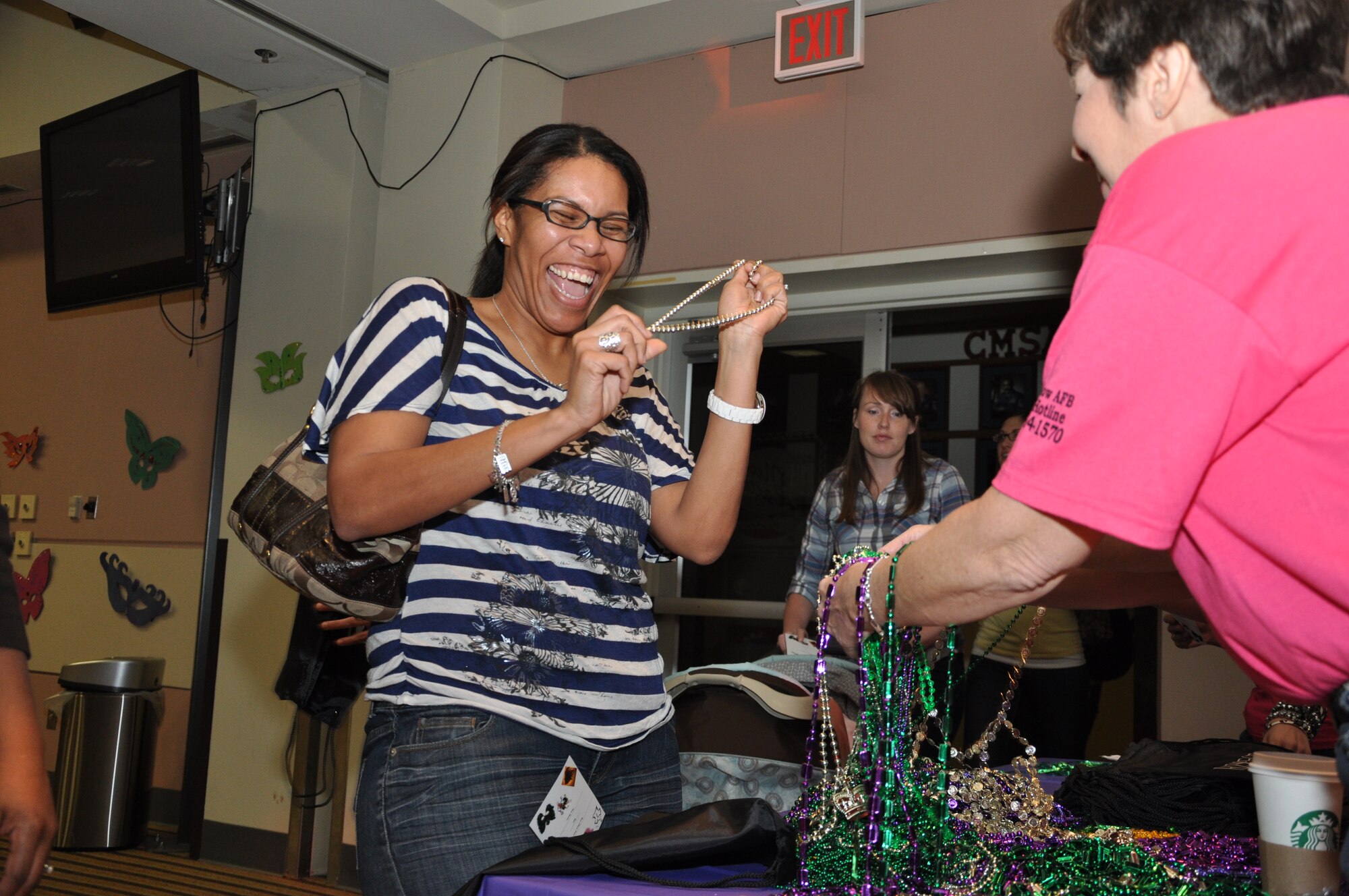 GOODFELLOW AIR FORCE BASE, Texas-- Subrina Russell, 17th Training Wing Spouse, laughs with surprised delight as Laurel Matus, Sexual Assault Prevention Response office, gives her a set of decorative beads as she enters the Event center Ballroom during ‘Ladies Night Out’ Feb. 23. More than 100 women attended the three-hour, educational event. (U.S. Air Force photo/Airman 1st Class Jessica Keith) 