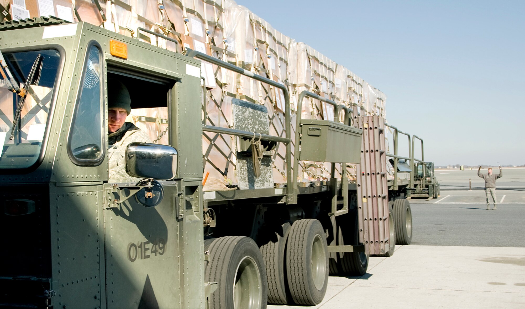 Senior Airman Seth Carpenter, left, drives a 60K Tunner Aircraft Loader away from the a cargo loading dock as Senior Airman Scott Munn directs, Feb. 13, 2012, at Dover Air Force Base, Del. Carpenter and Munn are Ramp Services transporters with the 436th Aerial Port Squadron. (U.S. Air Force photo by Master Sgt. Jeanette Spain)