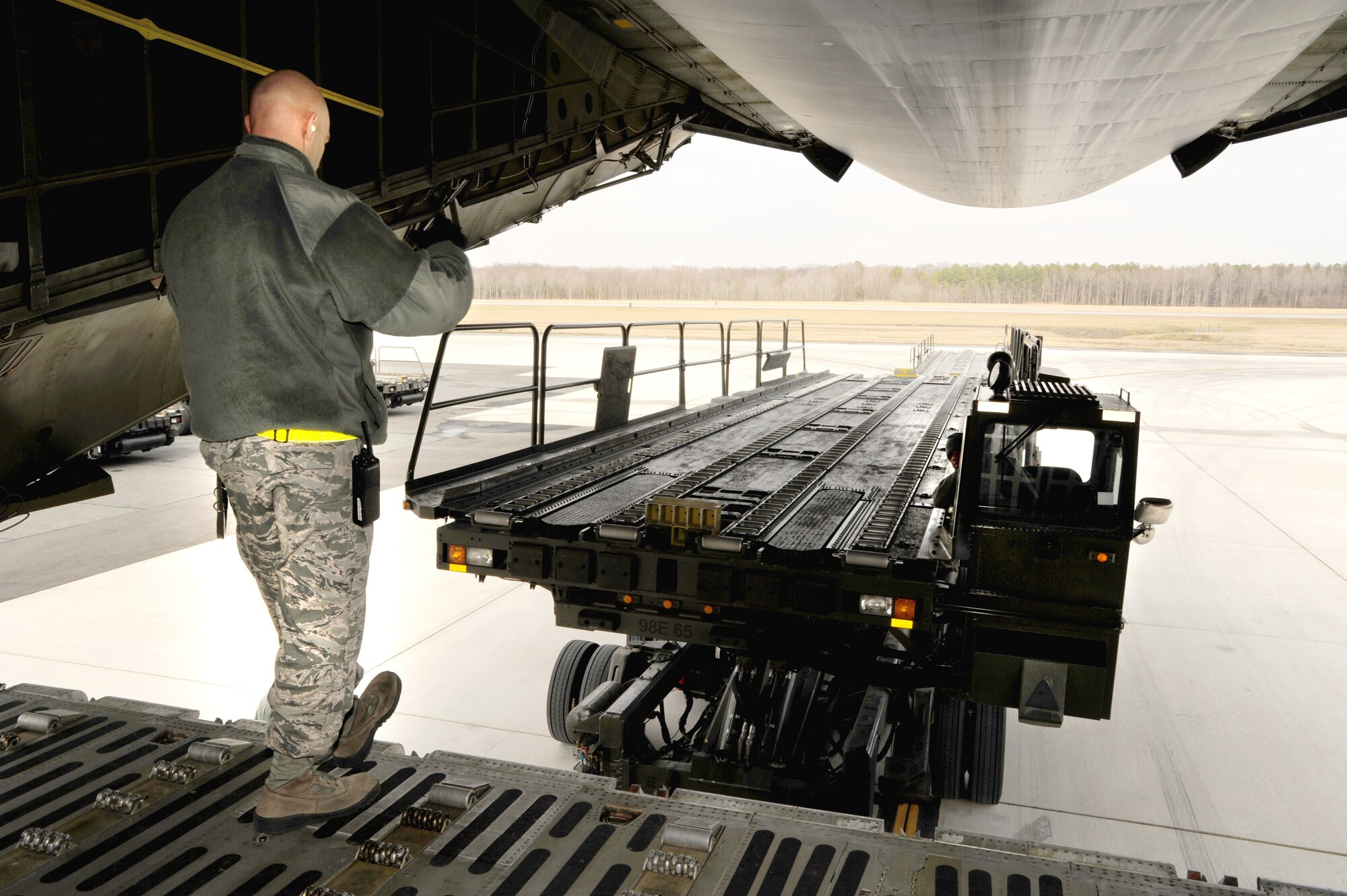 Staff Sgt. Jason Spenser, a Ramp Services transporter with the 436th Aerial Port Squadron, directs a 60K Tunner Aircraft Loader toward the rear of a C-17 Globemaster III prior to off-loading cargo pallets, Feb. 10, 2012, at Dover Air Force Base, Del. (U.S. Air Force photo by Master Sgt. Jeanette Spain)